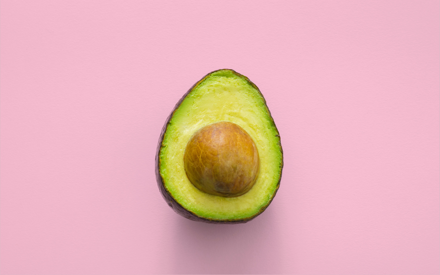 growth hacking Um abacate partido ao meio em um fundo cor de rosa. Passando a ideia de dúvida se é de comer ou passar no cabelo
